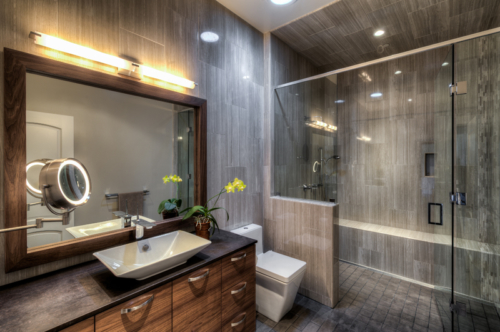 Modern luxury bath with vessel sink, wall mounted toilet and glass walk-in shower that is ADA compliant