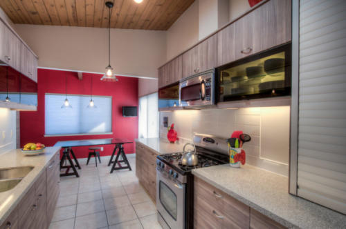 Modern style kitchen with lift up cabinet doors and red accent wall.