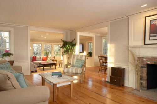 Open concept floor plan living room with wide plank pine floors and fireplace. Expansive living area with fireplace, wide-plank flooring and plenty of natural light.