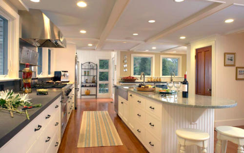 Updated kitchen with island, grey countertops and original wide-plank pine flooring.